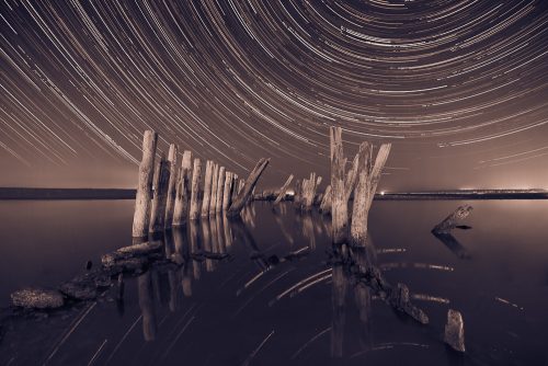 Pillars in the water at night on a background star trails