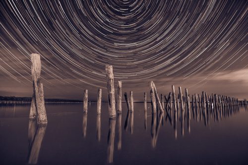 Pillars in the water at night on a background star trails