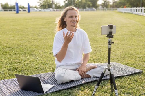 Happy,Yoga,Coach,Sitting,In,Easy,Pose,Near,Laptop,And