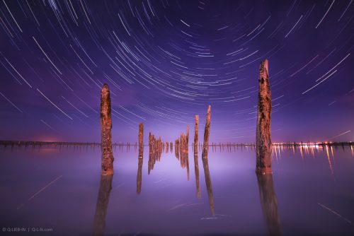 Poles in the water at night on a background star trails
