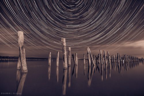 Pillars in the water at night on a background star trails